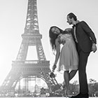 photo couple en noir et blanc posant devant la tour eiffel à Paris. Les mariés pose de face, dans les bras, la mariée cambre son bruste de façon gracieuse avec son bouquet de fleurs.