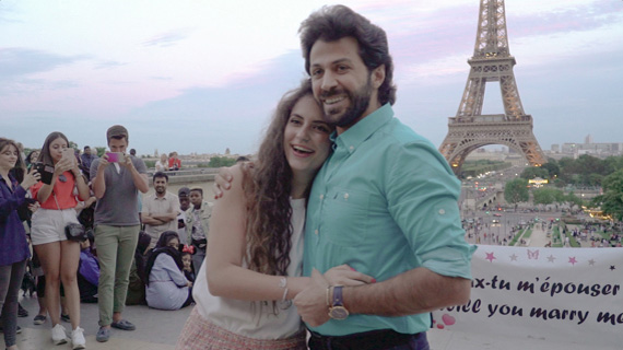 photo de demande en mariage surprise romantique devant la tour eiffel à Paris au milieu de la foule de touristes. Pancarte avec le message ecrit veux-tu m'épouser et would you marry me. 