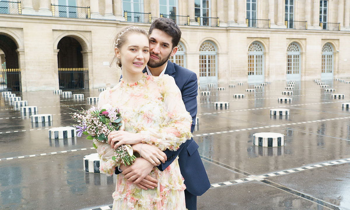 photo de mariage au palais royal. Le couple de mariés pose dans les bras. La mariée tient un bouquet de fleurs.