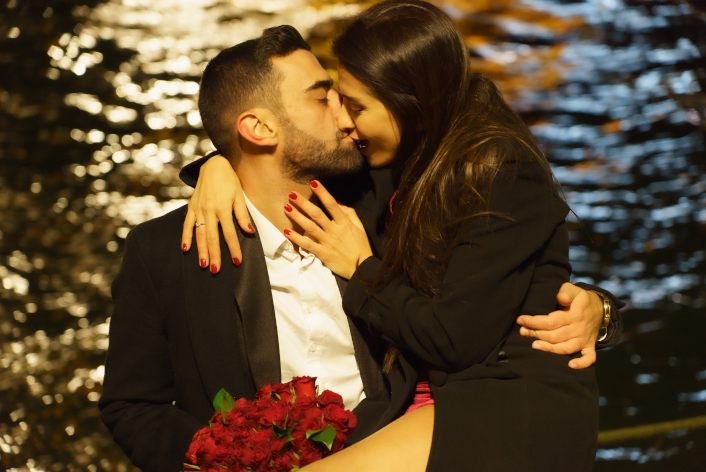 couple s'embrasse avec un bouquet de rose rouge devant la seine de nuit sur le port debilly Paris France