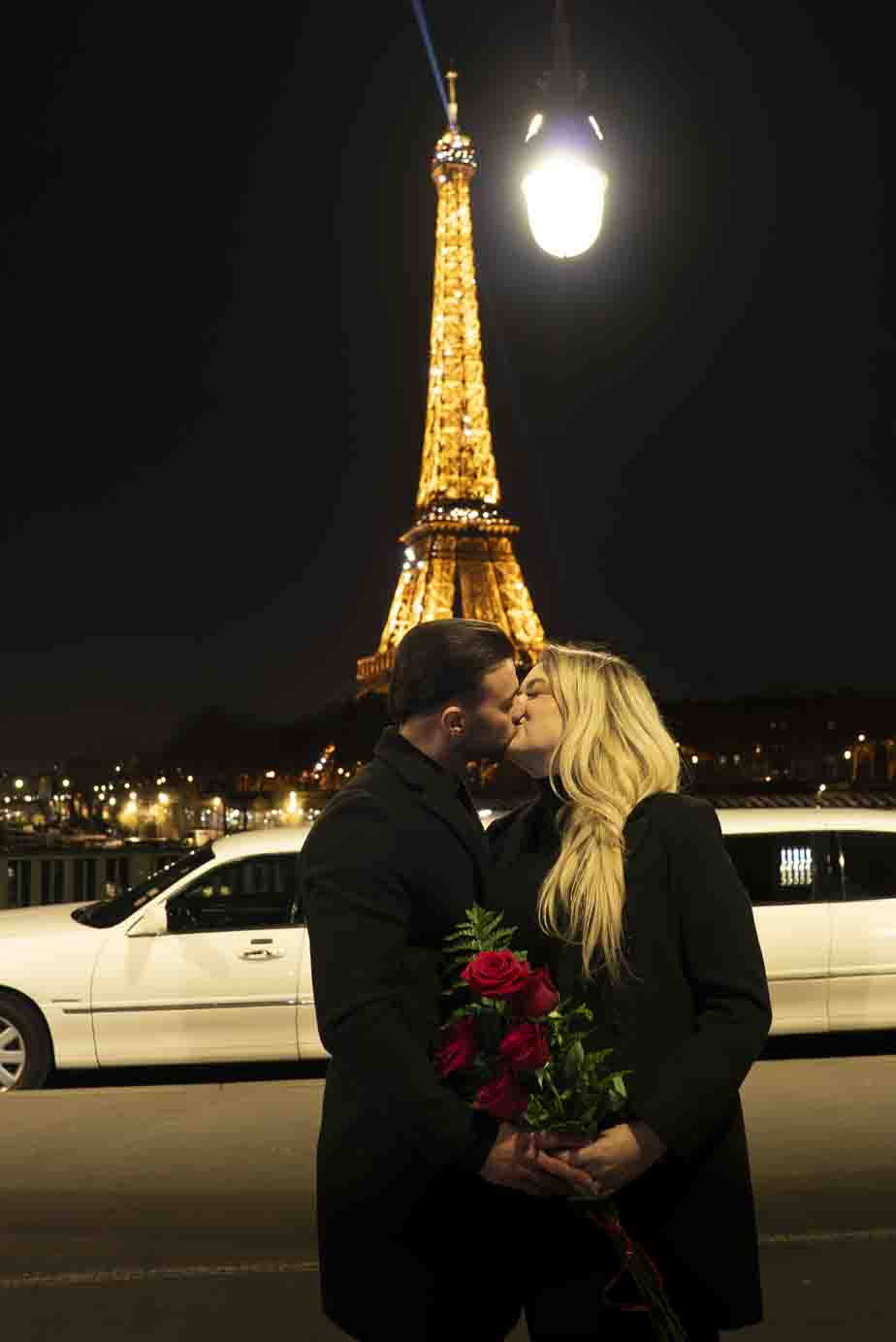 Séance photo romantique à Paris : couple enlacé sur le pont Bir-Hakeim avec la Tour Eiffel illuminée en arrière-plan.