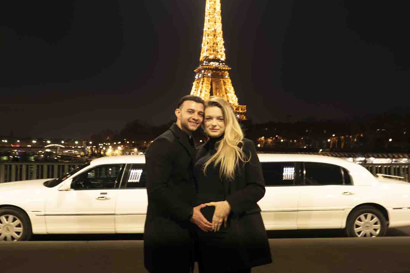 Séance photo romantique à Paris : couple heureux et future maman devant la Tour Eiffel illuminée.