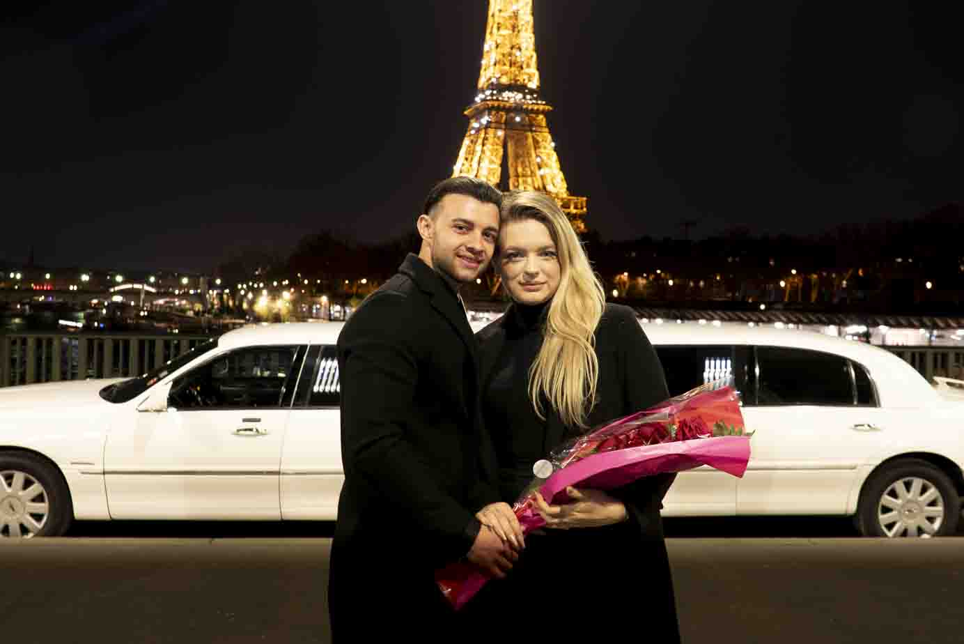 Photographe demande en mariage Paris : couple romantique avec bouquet de roses sur le pont Bir-Hakeim, Tour Eiffel illuminée en arrière-plan.