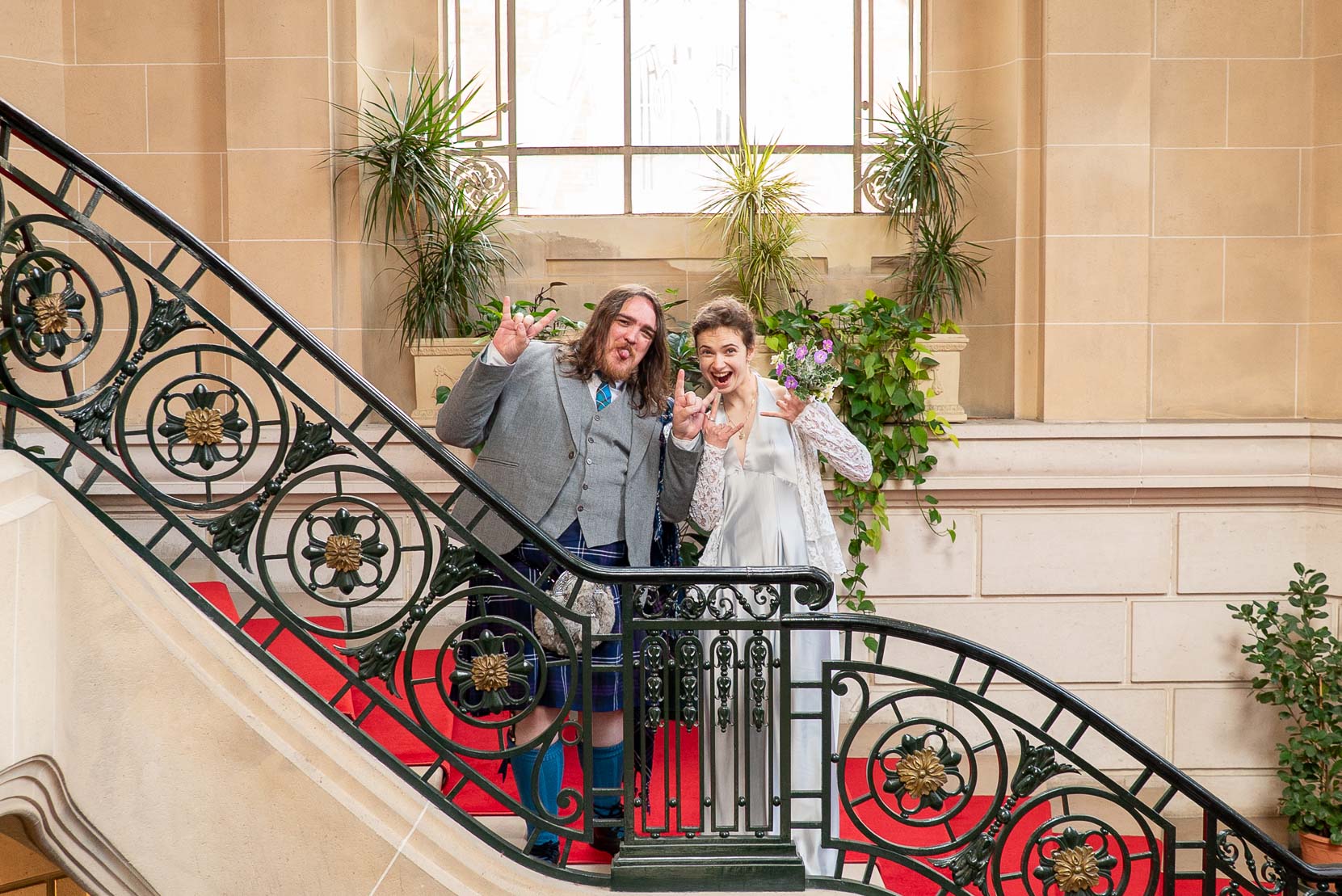 Mariés dans les escaliers d'honneur de la mairie du 19e — moment complice et humoristique, photo mariage Paris naturel