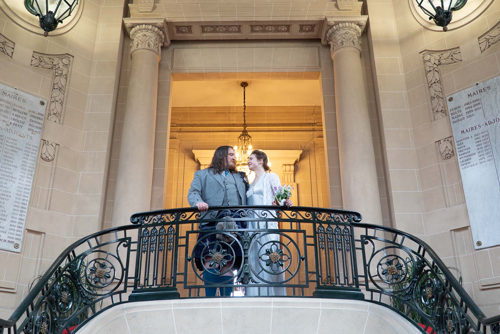 Mariés avançant côte à côte dans les escaliers d'honneur de la mairie du 19e à Paris