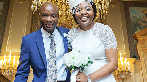 Photo de couple de mariage noir heureux sous un lustre doré de la salle des mariages de la mairie de paris 13e