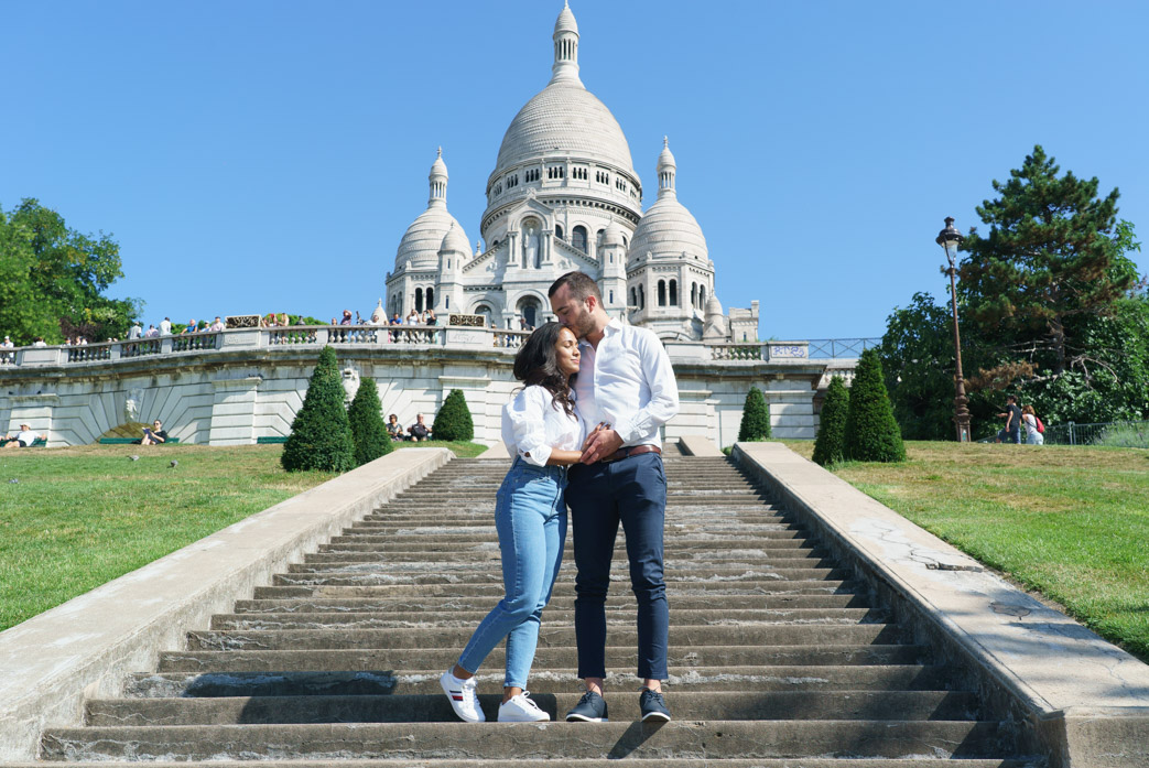 couple d'amoureux dans les bras après une demande en mariage à Montmartre avec le sacré-coeur en arrière plan
