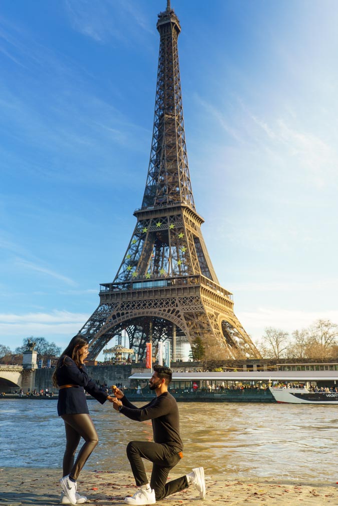 demande en mariage à Paris, surprise, expression de joie sur le visage de la fiancée, fiancé mettant la bague au doigt, demande en mariage devant la Tour Eiffel, quai de Seine, Port Debilly, Paris, après-midi d'hiver en janvier, ciel bleu, lumière dorée du soleil